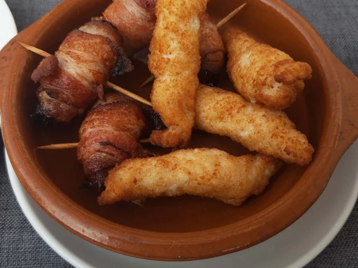 Skewers of fried chicken and bacon in a clay dish