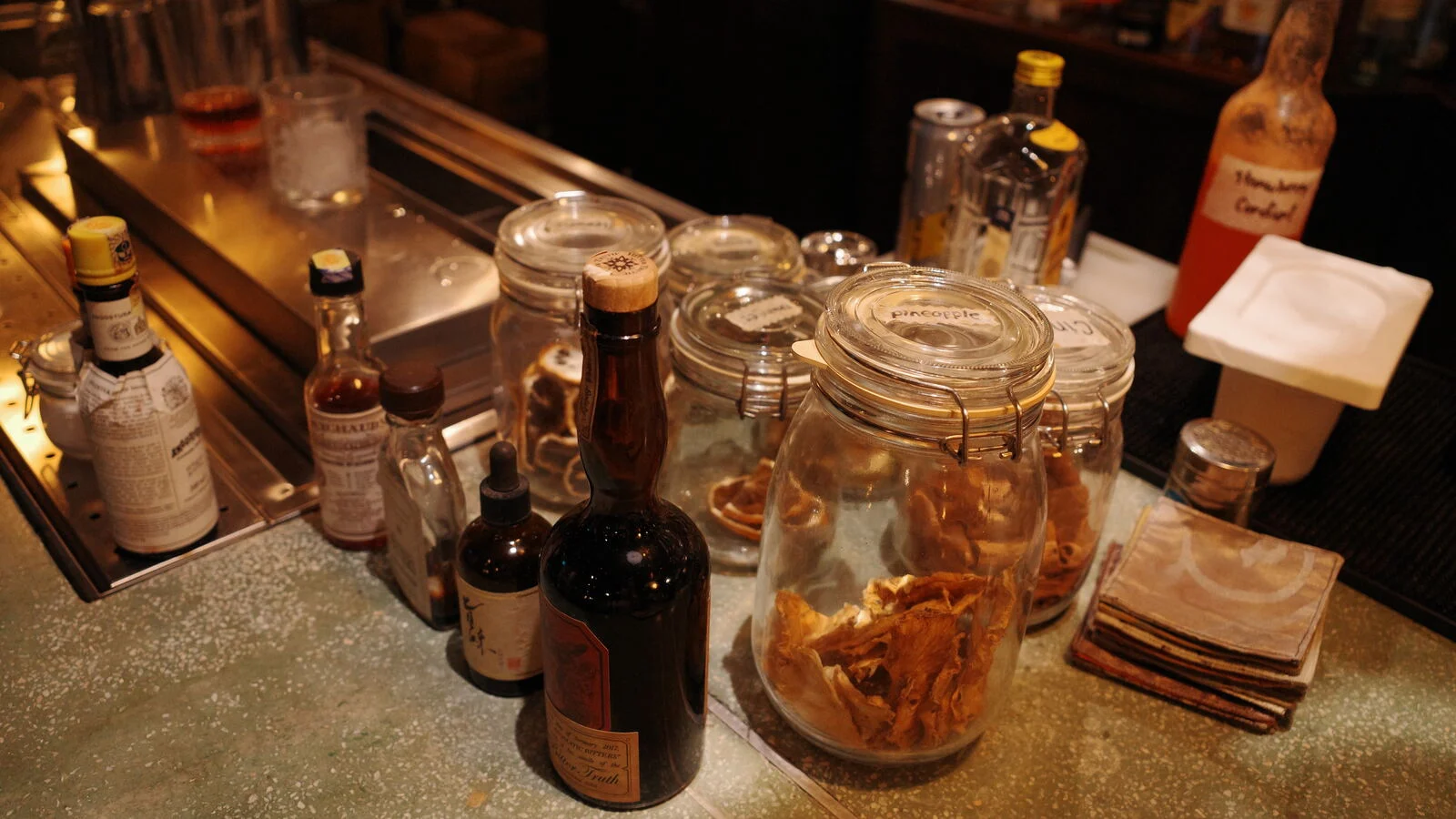 Bottles and jars on a bar counter in warm light