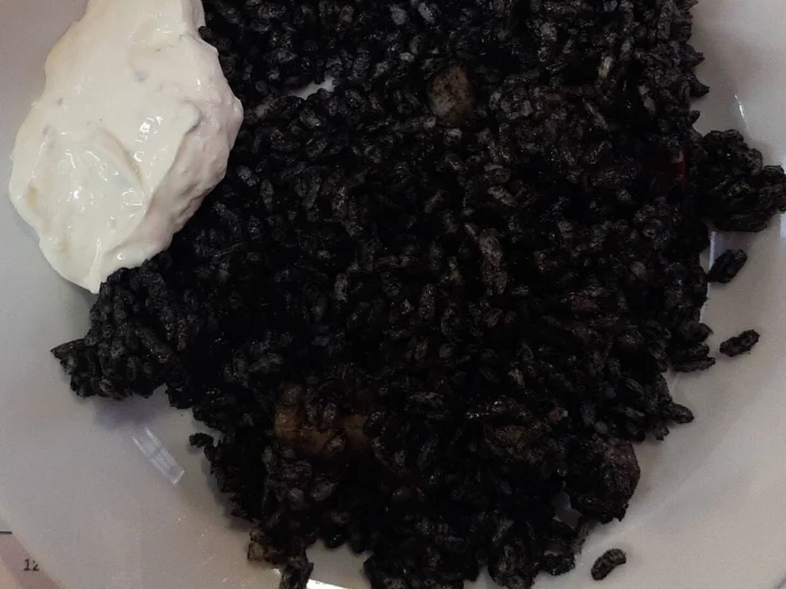 Black squid-ink rice with alioli on a white plate
