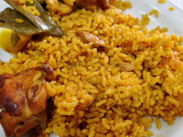 A plate of paella with pieces of chicken