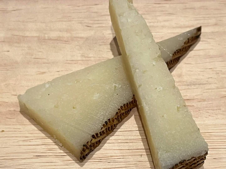 Two wedges of cured cheese on a wooden board