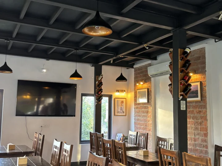 A restaurant dining room with dark beams and pendant lamps