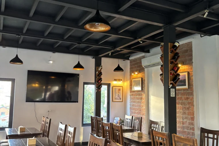 A restaurant dining room with dark beams and pendant lamps