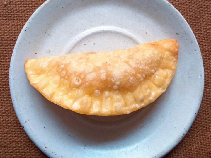 A fried pastry half-moon on a blue plate