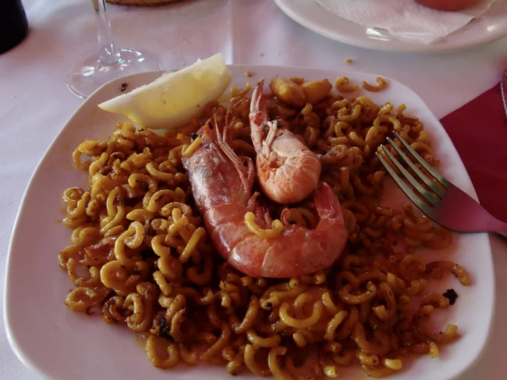 Toasted noodles with a langoustine on a white plate
