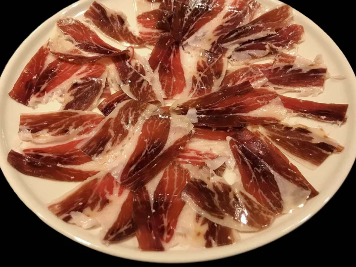 Thin slices of cured ham fanned across a plate