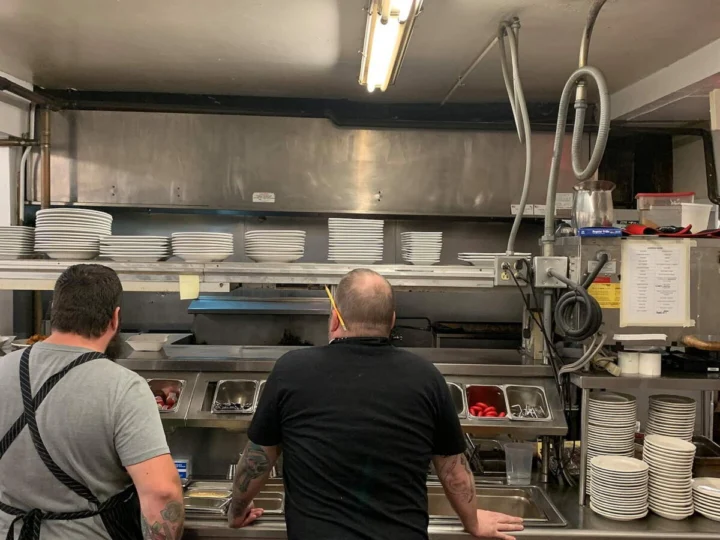 Two cooks at work in a restaurant kitchen, seen from behind