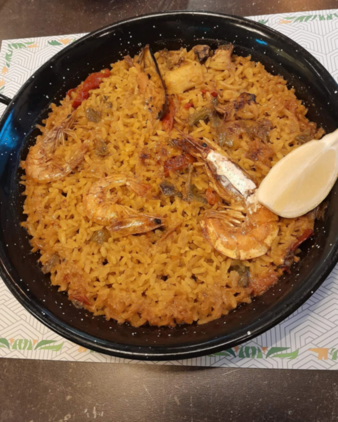A finished paella in its pan with a lemon wedge, from above