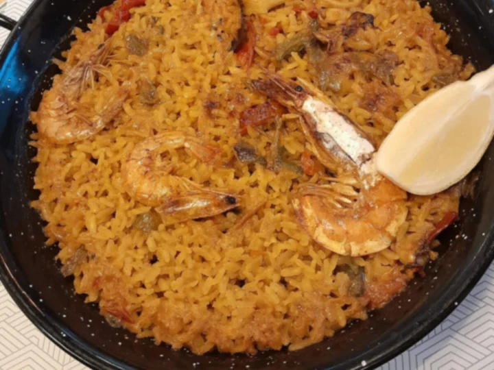 A finished paella in its pan with a lemon wedge, from above