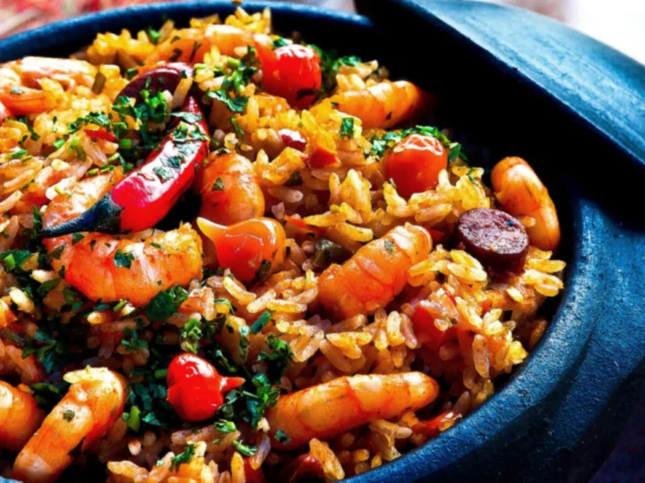 A paella with prawns and chorizo in a dark pan