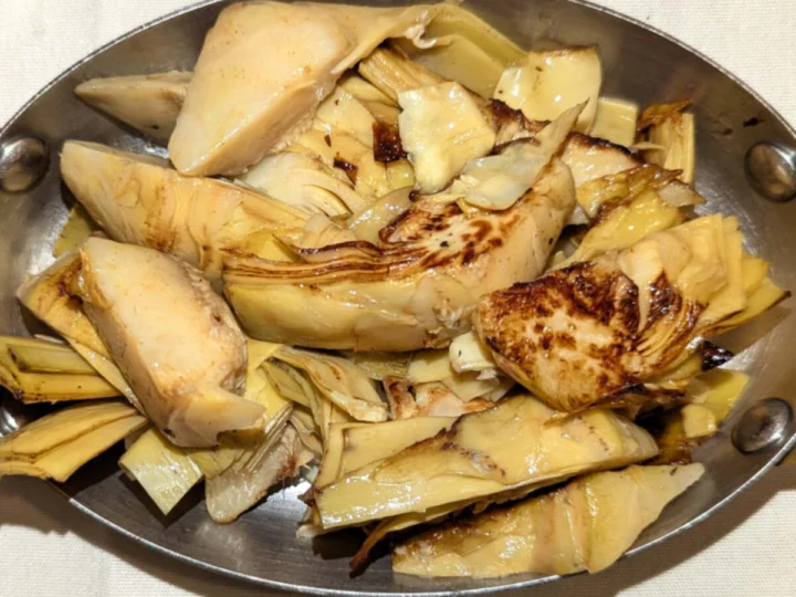 Roasted artichoke halves in a brass pan