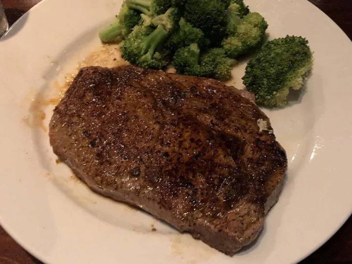 A grilled steak with broccoli on a white plate