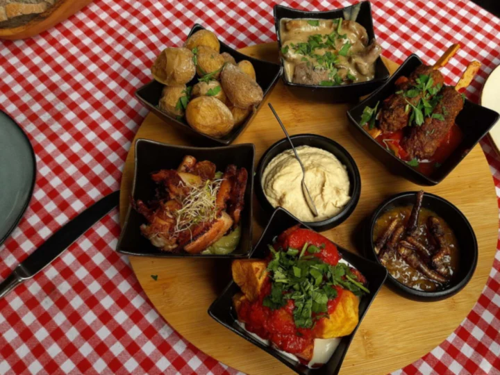 Small plates of tapas on a wooden board over a checked cloth