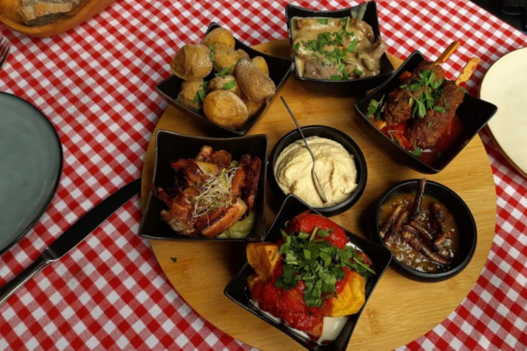 Small plates of tapas on a wooden board over a checked cloth