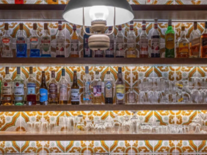 A bar with a patterned tile wall and shelves of bottles