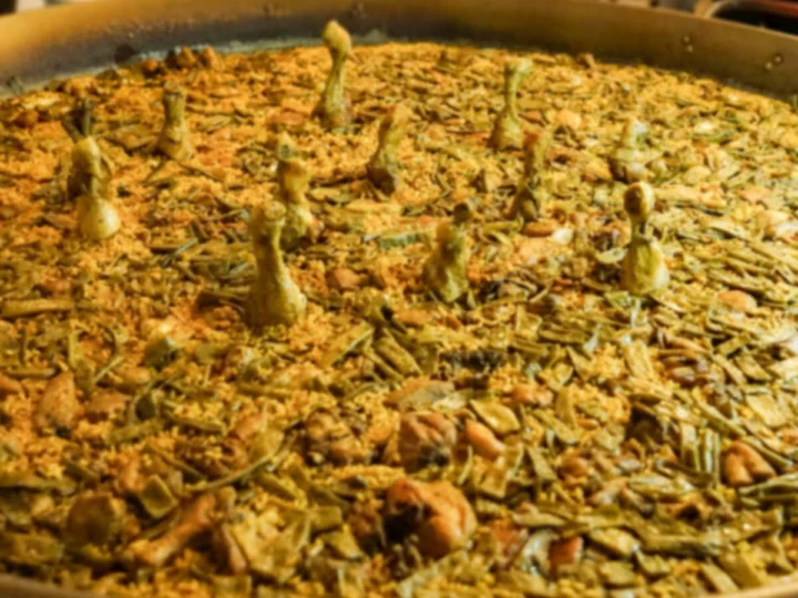 A wide pan of paella with green vegetables